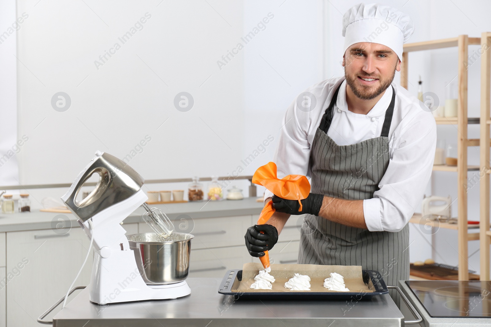 Photo of Pastry chef preparing meringues at table in kitchen