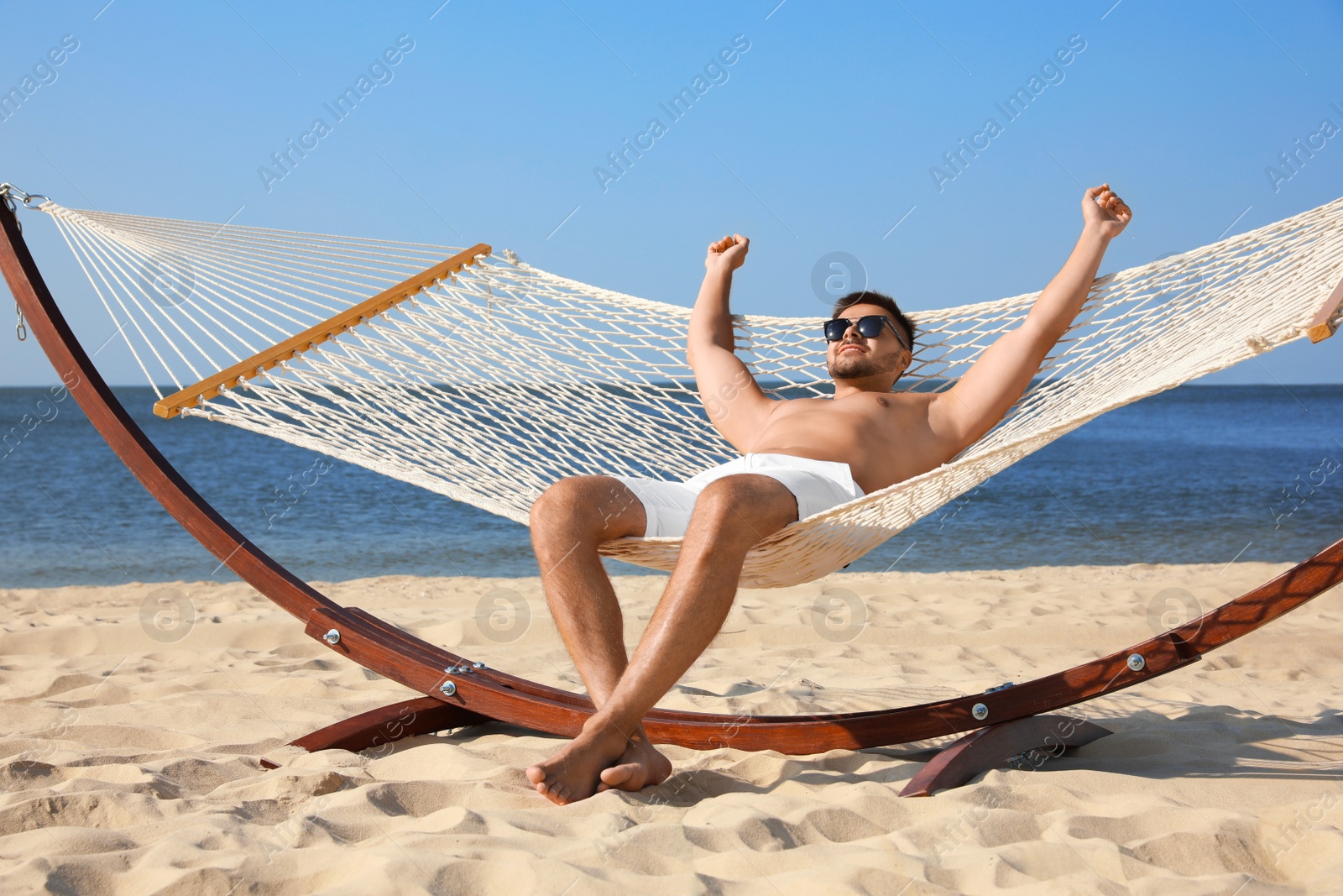 Photo of Young man relaxing in hammock on beach