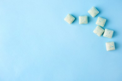 Tasty chewing gums on light blue background, flat lay. Space for text