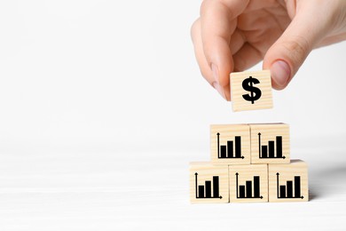 Image of Woman putting cube with dollar sign on other ones with charts against white background, closeup