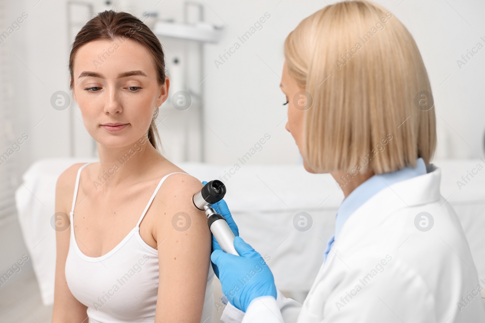 Photo of Dermatologist with dermatoscope examining patient in clinic