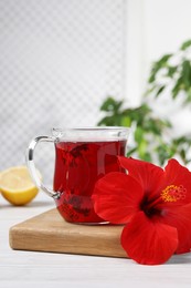 Delicious hibiscus tea and beautiful flower on white wooden table, space for text