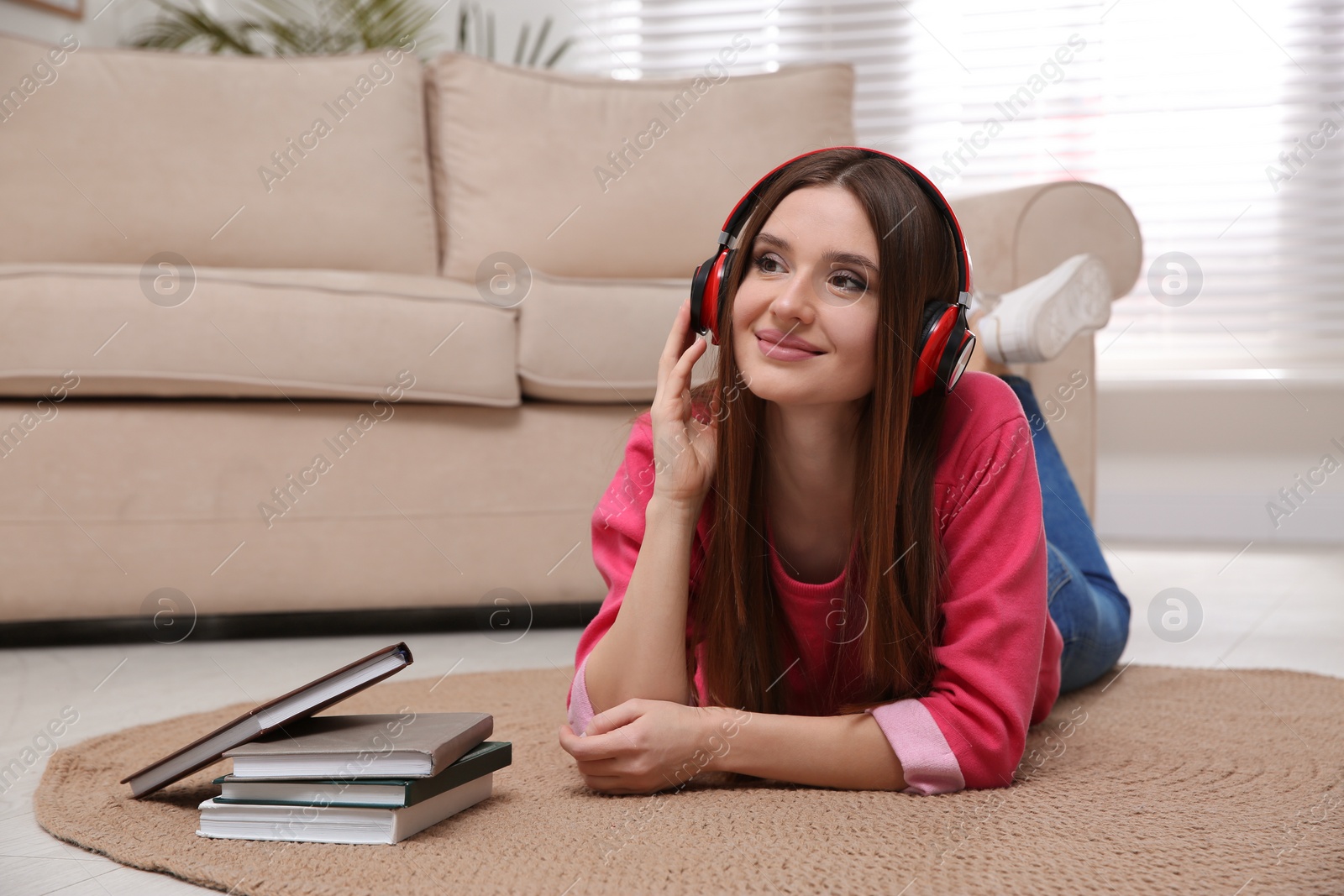 Photo of Woman listening to audiobook lying on floor at home

