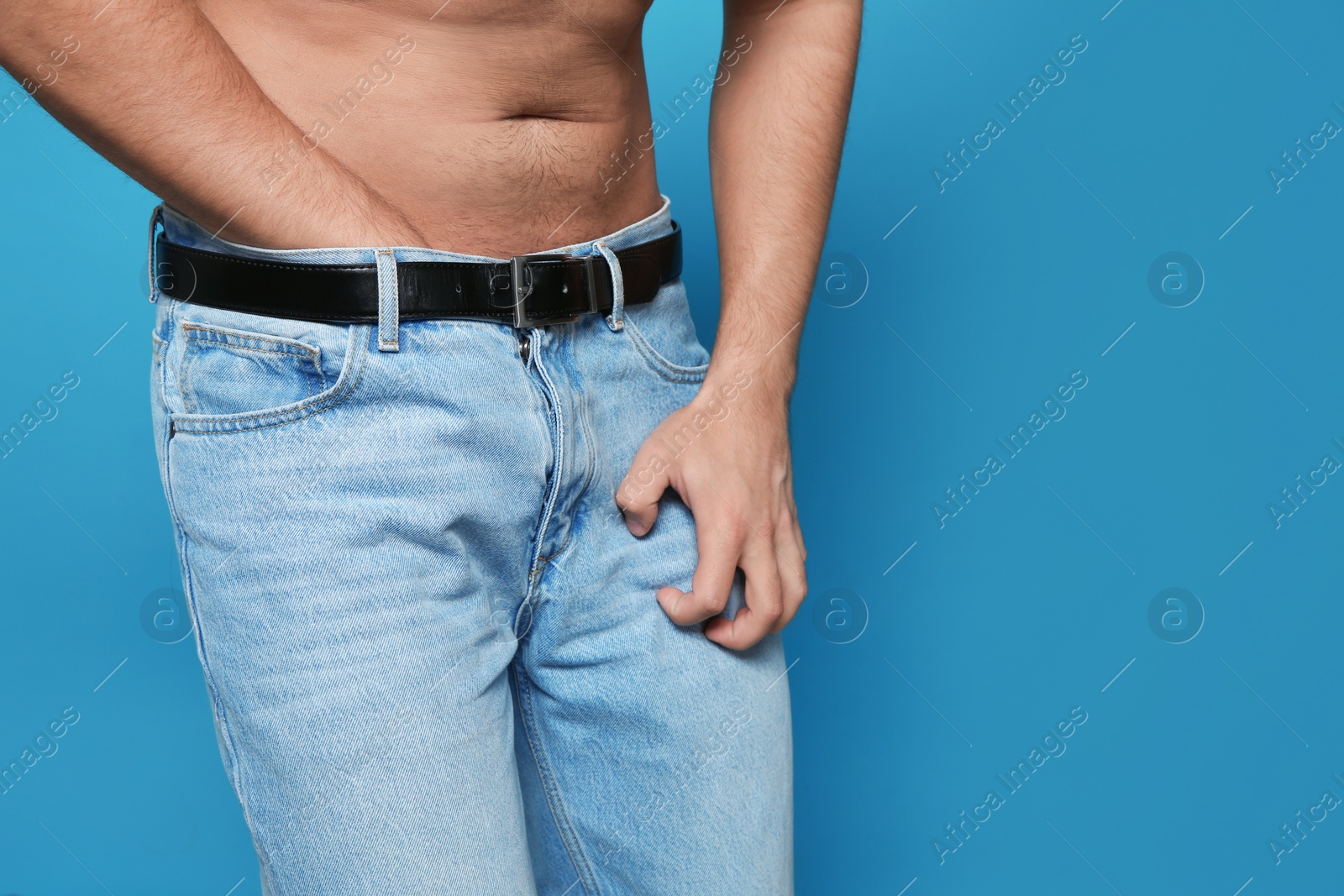 Photo of Man scratching crotch on color background, closeup. Annoying itch