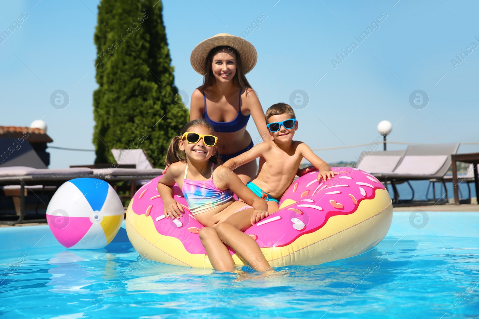 Photo of Woman with her children in swimming pool. Family vacation