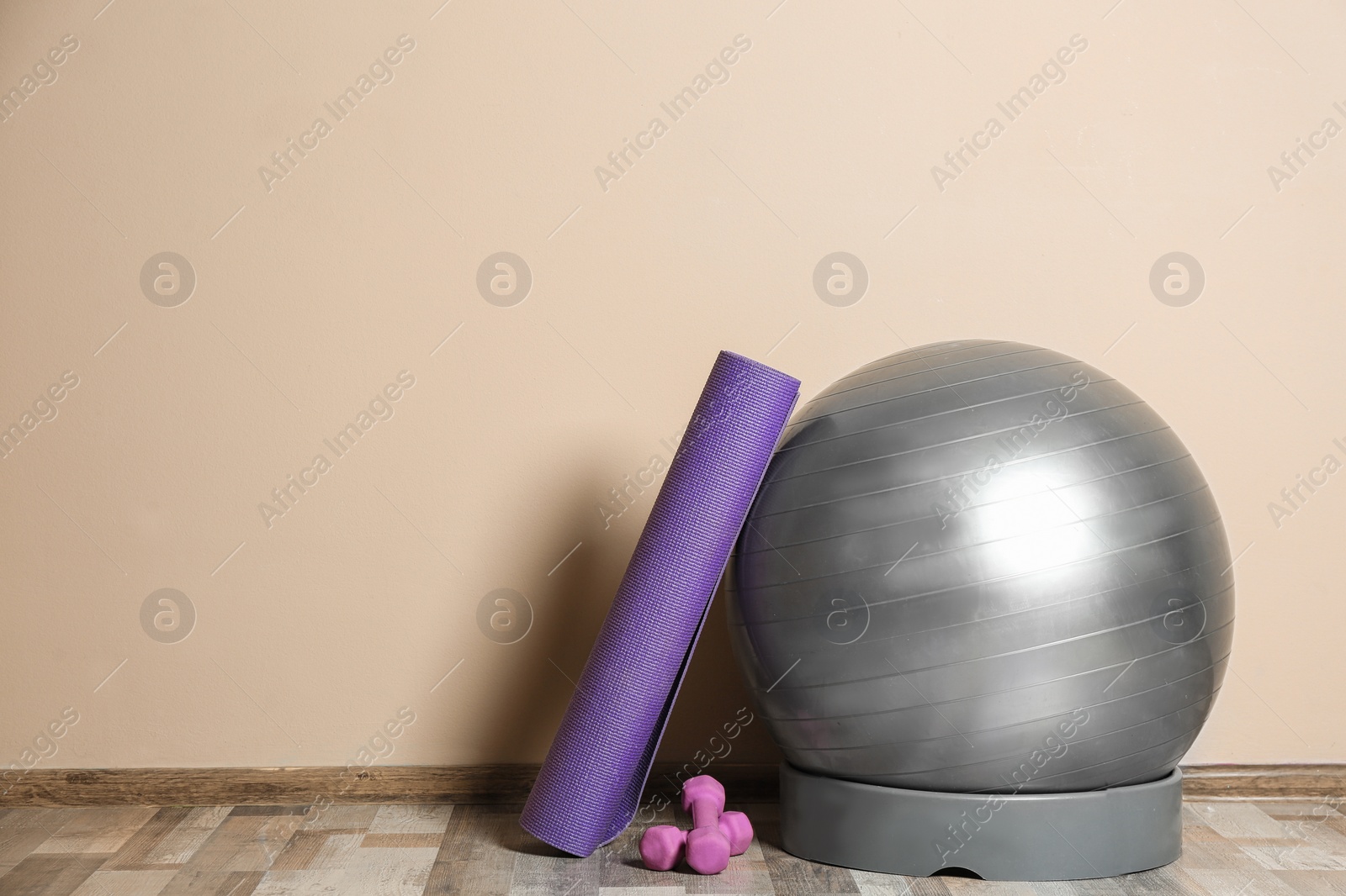 Photo of Set of fitness inventory on floor near color wall. Space for text