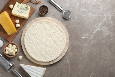 Flat lay composition with pizza crust and fresh ingredients on table. Space for text