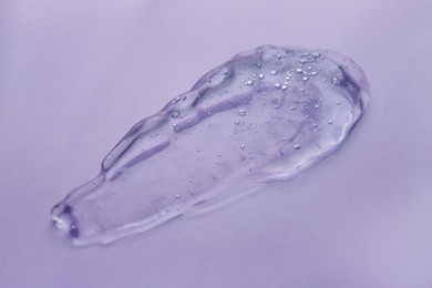 Sample of transparent shower gel on violet background