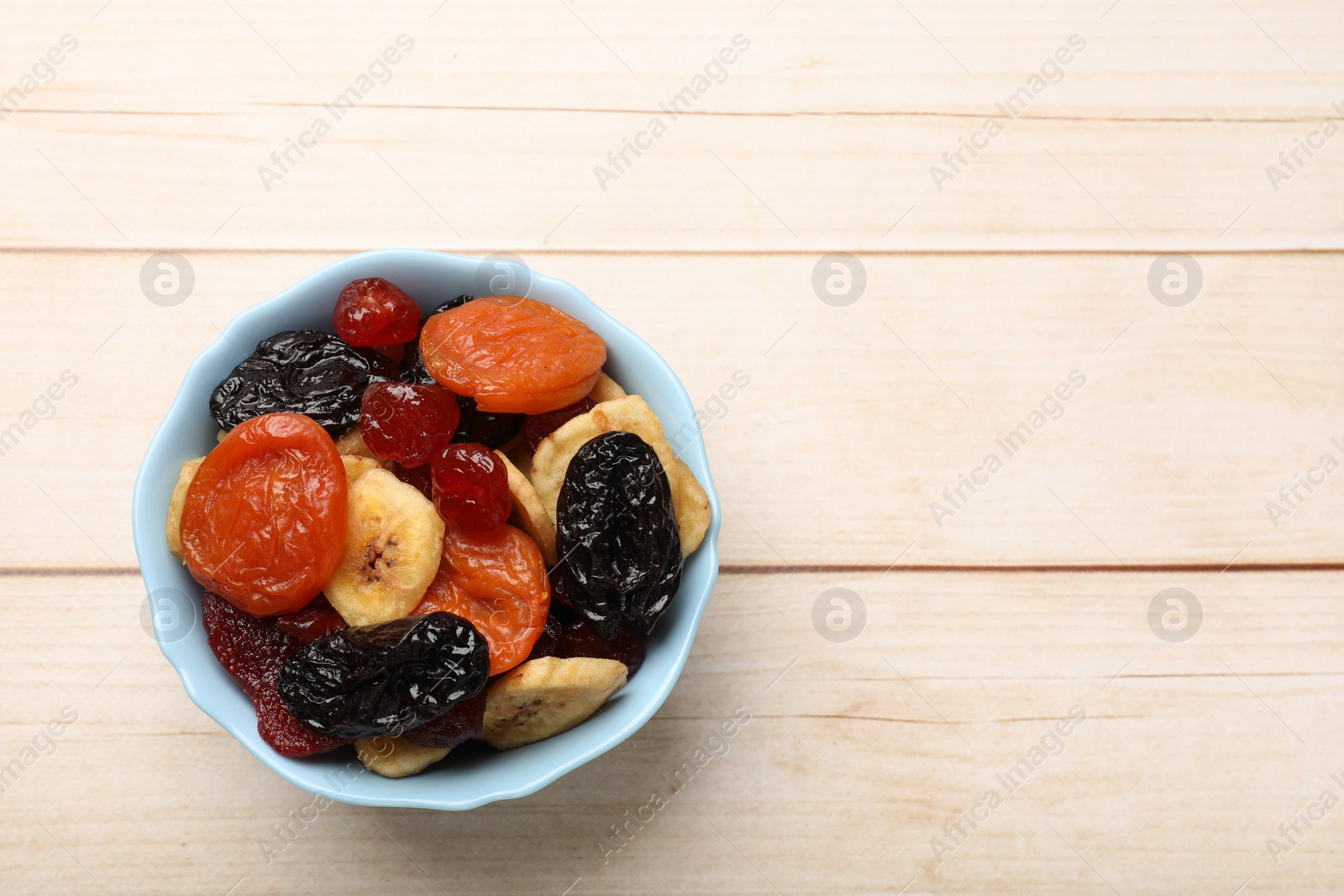 Photo of Mix of delicious dried fruits on white wooden table, top view. Space for text