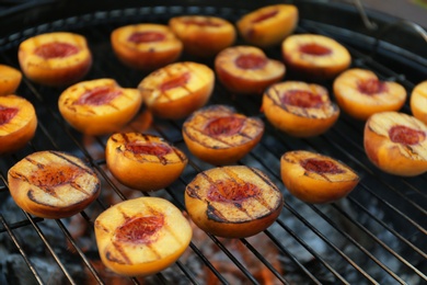 Photo of Modern grill with tasty cut peaches, closeup