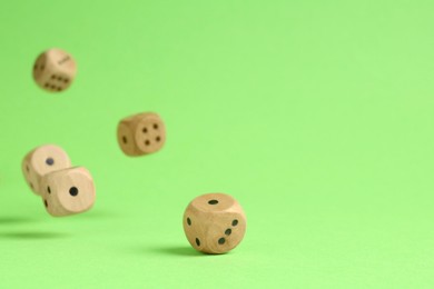 Photo of Many wooden game dices falling on green background. Space for text