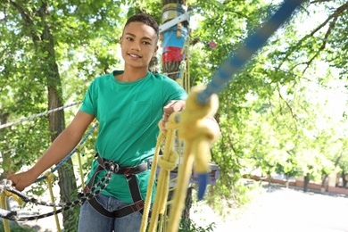 Photo of African-American teenage boy climbing in adventure park. Summer camp