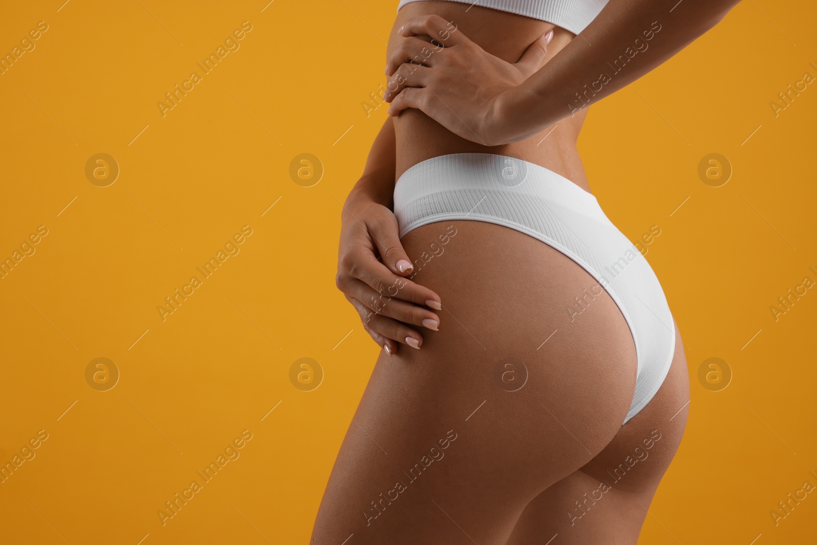 Photo of Young woman in stylish white bikini on orange background, closeup. Space for text