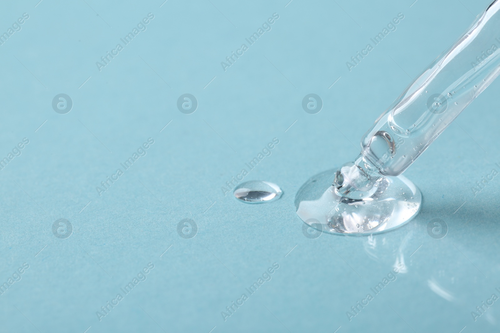 Photo of Pipette with cosmetic serum on light blue background, closeup. Space for text