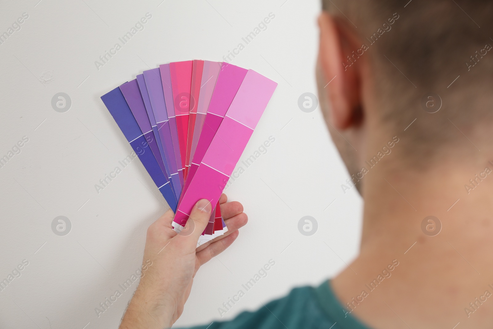 Photo of Man with palette choosing color for painting wall indoors, closeup. Interior design