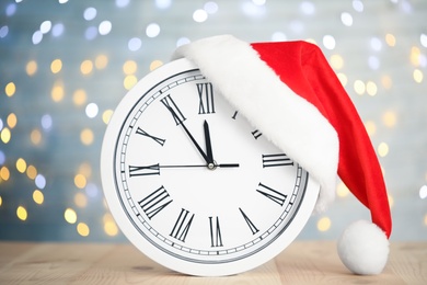 Clock with Santa hat showing five minutes until midnight on blurred background. New Year countdown