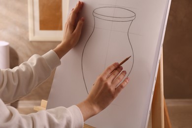 Woman drawing vase with graphite pencil on canvas indoors, closeup