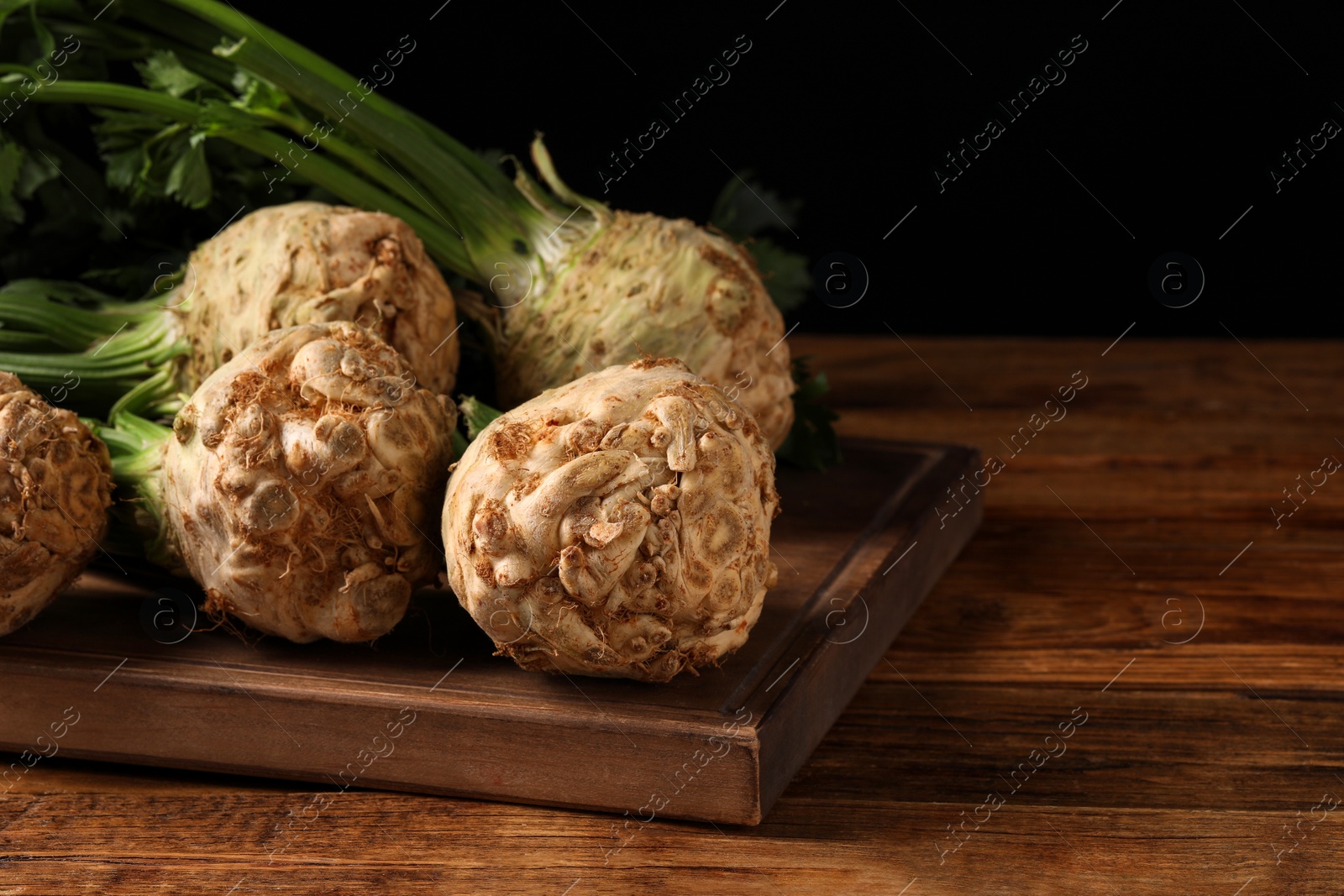 Photo of Fresh raw celery roots on wooden table. Space for text