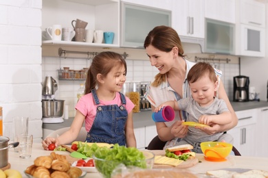 Housewife preparing dinner with her children on kitchen