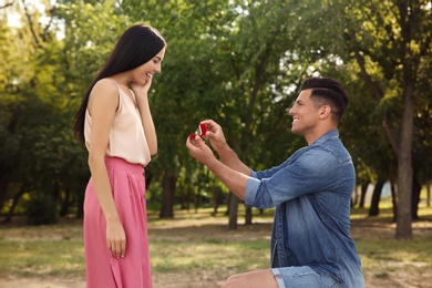 Photo of Man with engagement ring making proposal to his girlfriend in park