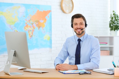 Male consultant working with computer in travel agency