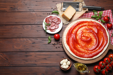 Photo of Flat lay composition with base and ingredients on wooden table, space for text. Pepperoni pizza recipe