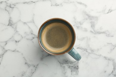 Photo of Tasty coffee in cup on white marble table, top view