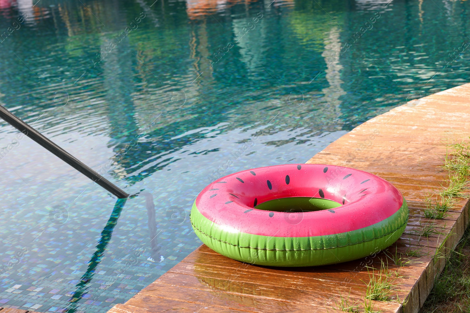 Photo of Inflatable ring on wooden deck near swimming pool. Luxury resort