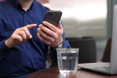 Photo of Man using smartphone at table in cafe, closeup