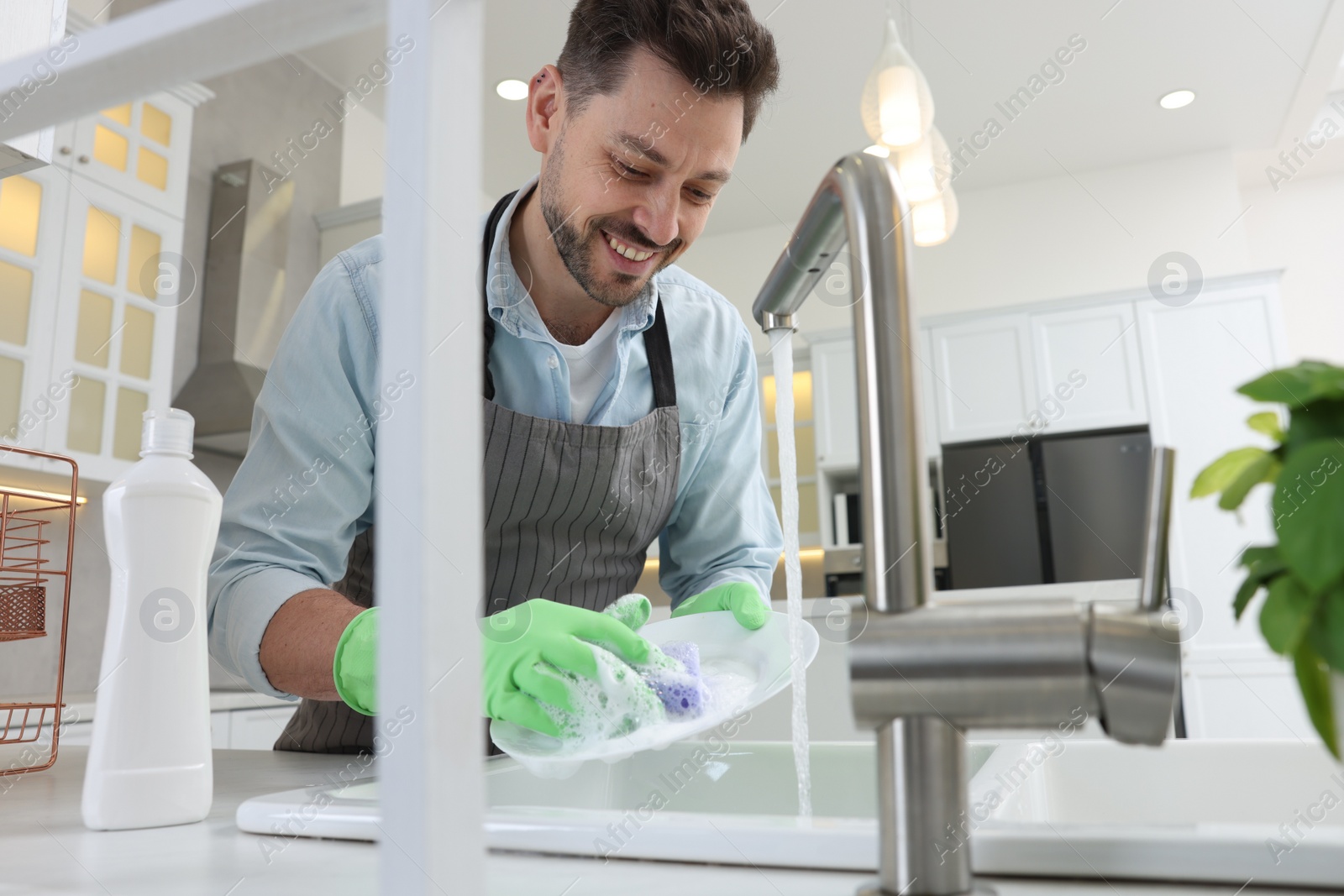 Photo of Man washing plate above sink in kitchen