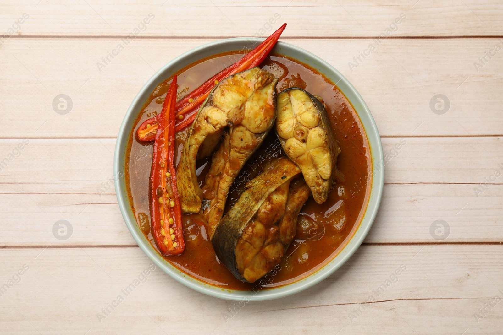 Photo of Tasty fish curry on white wooden table, top view. Indian cuisine