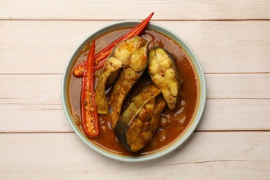 Photo of Tasty fish curry on white wooden table, top view. Indian cuisine