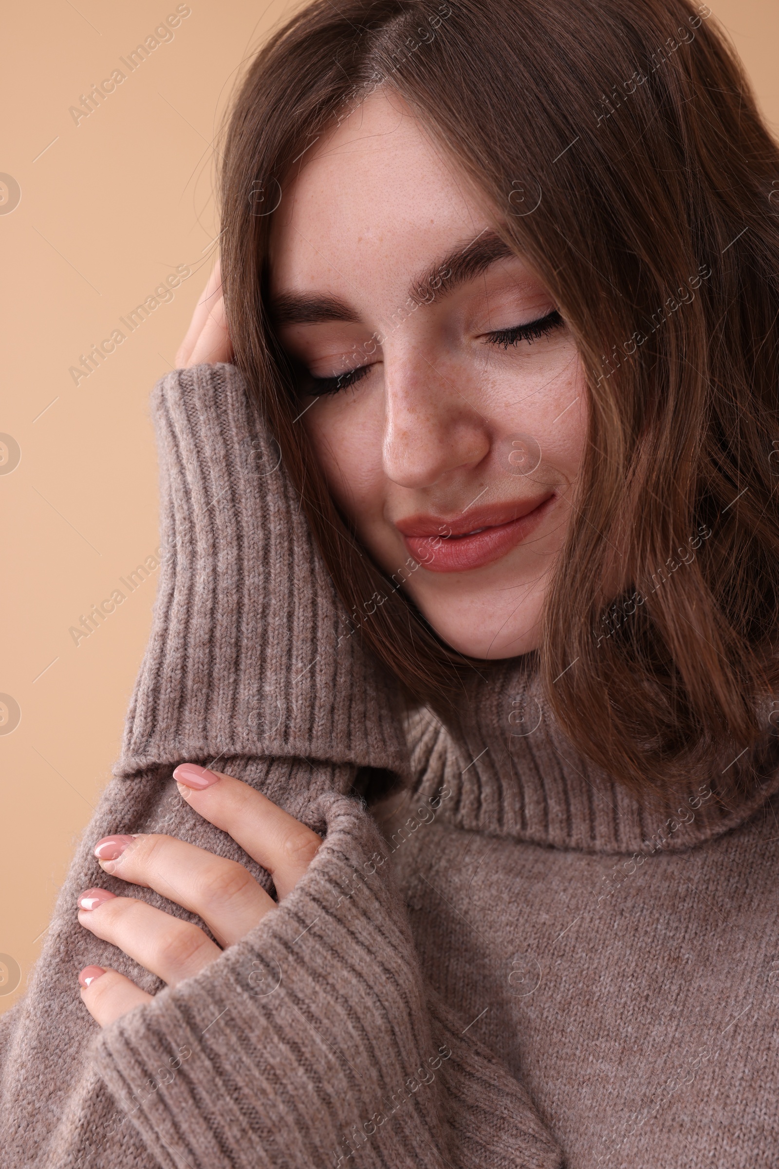 Photo of Portrait of beautiful young woman in warm sweater on brown background