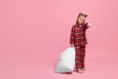 Photo of Girl in pajamas with pillow sleepwalking on pink background, space for text