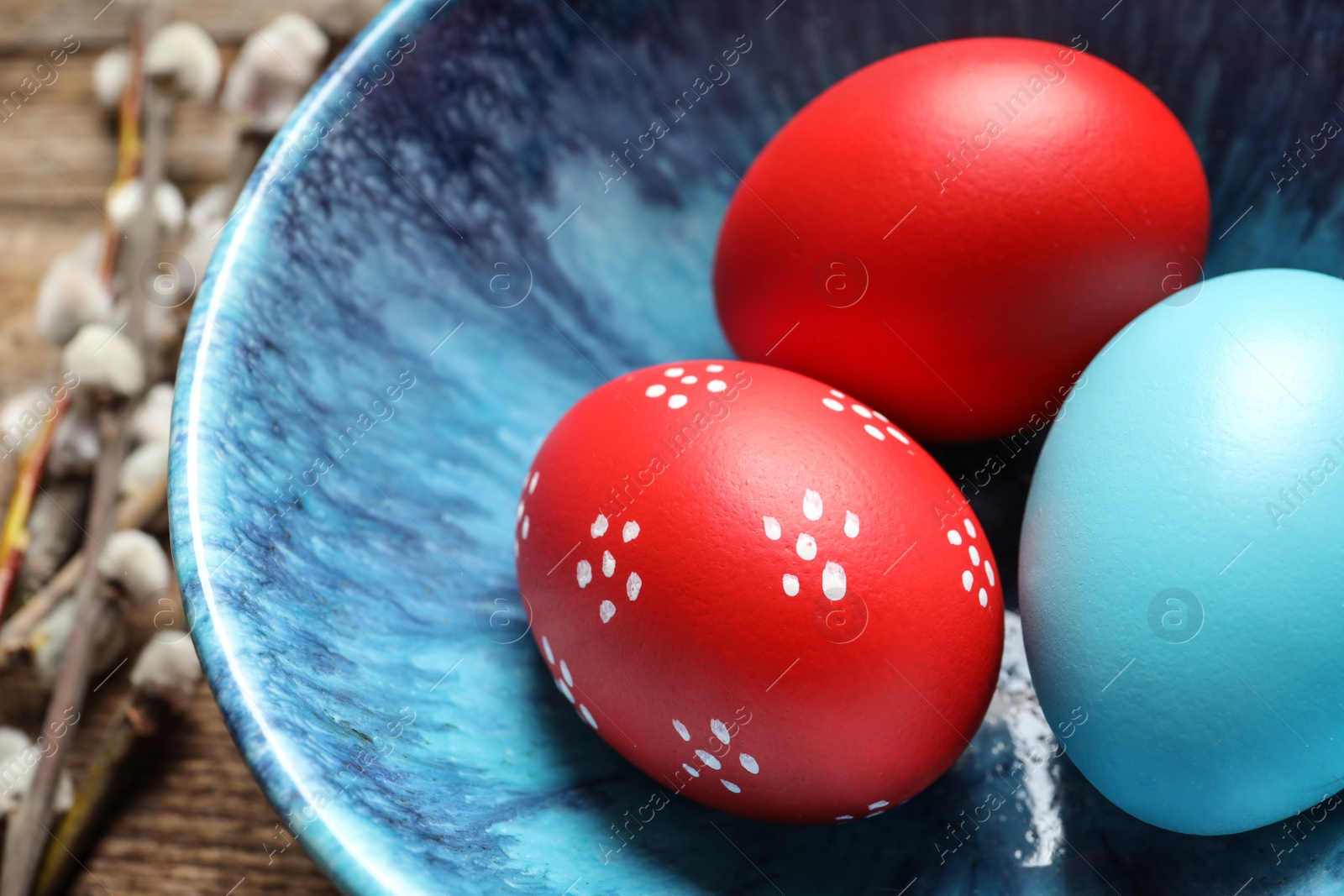 Photo of Bowl with painted Easter eggs on table, closeup