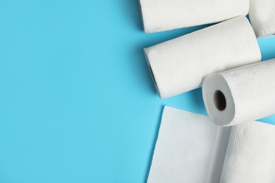 Photo of Rolls of paper towels on light blue background, space for text