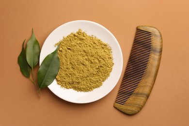Photo of Henna powder, comb and green leaves on coral background, flat lay. Natural hair coloring