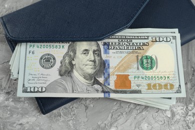 Photo of Money exchange. Wallet with dollar banknotes on grey stone background