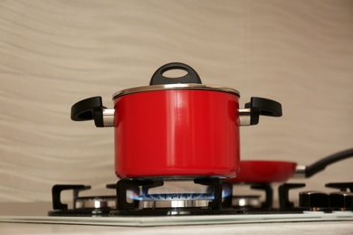 Photo of Red pot and frying pan on modern gas stove