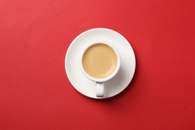 Photo of Aromatic coffee in cup on red background, top view