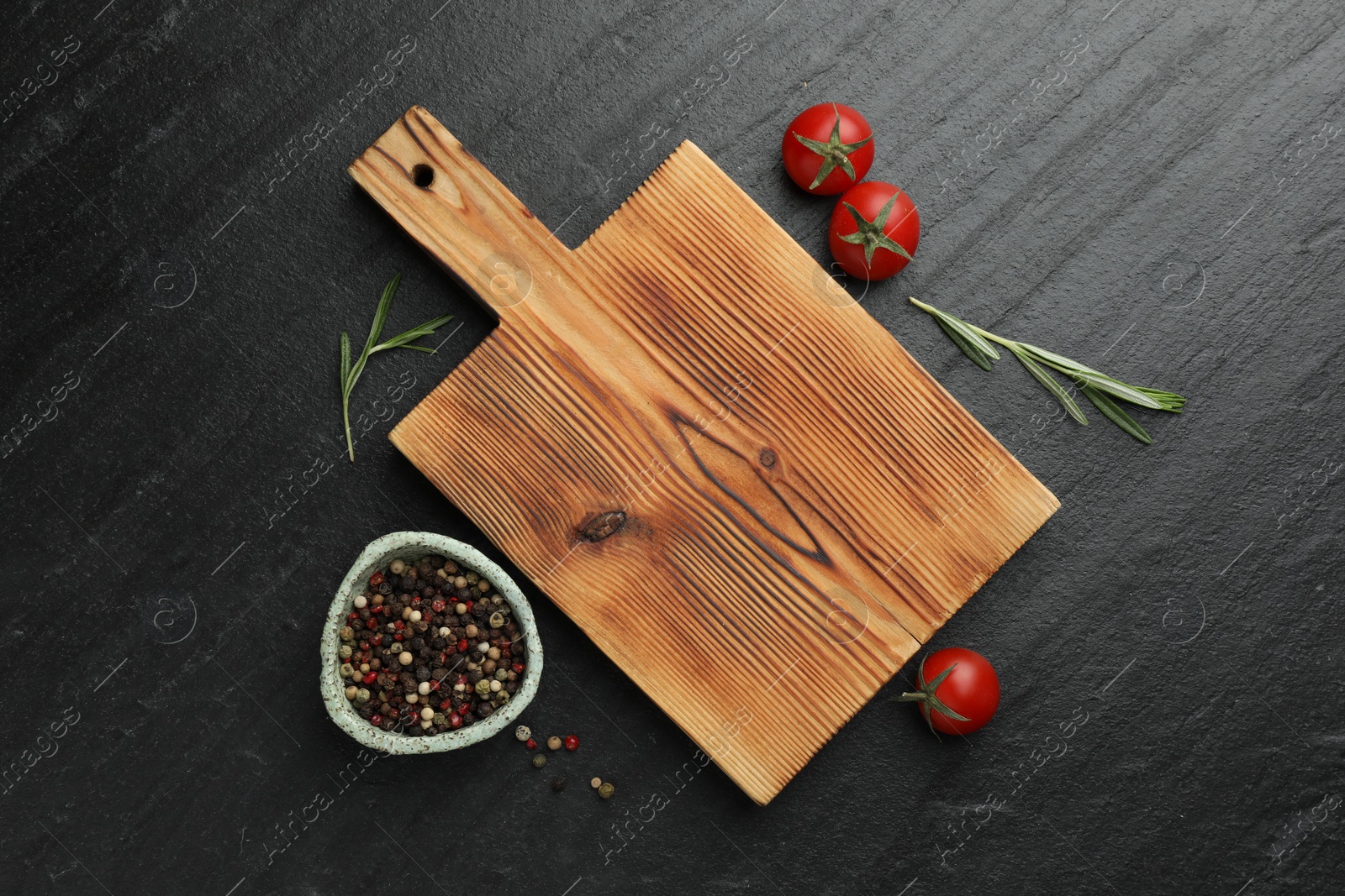 Photo of Wooden cutting board, fresh tomatoes and different spices on grey textured table, flat lay