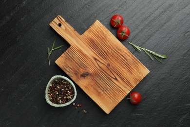 Photo of Wooden cutting board, fresh tomatoes and different spices on grey textured table, flat lay