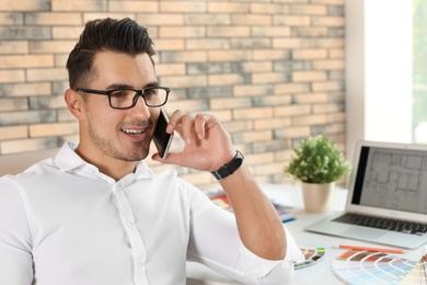 Handsome young man talking on phone in office