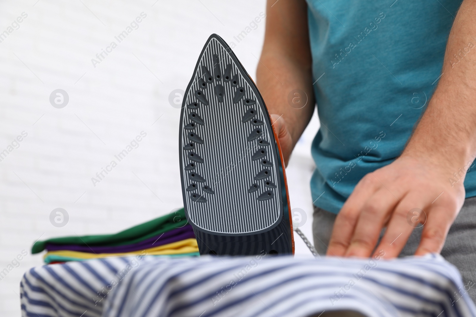 Photo of Man ironing shirt on board at home, closeup