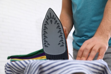 Man ironing shirt on board at home, closeup