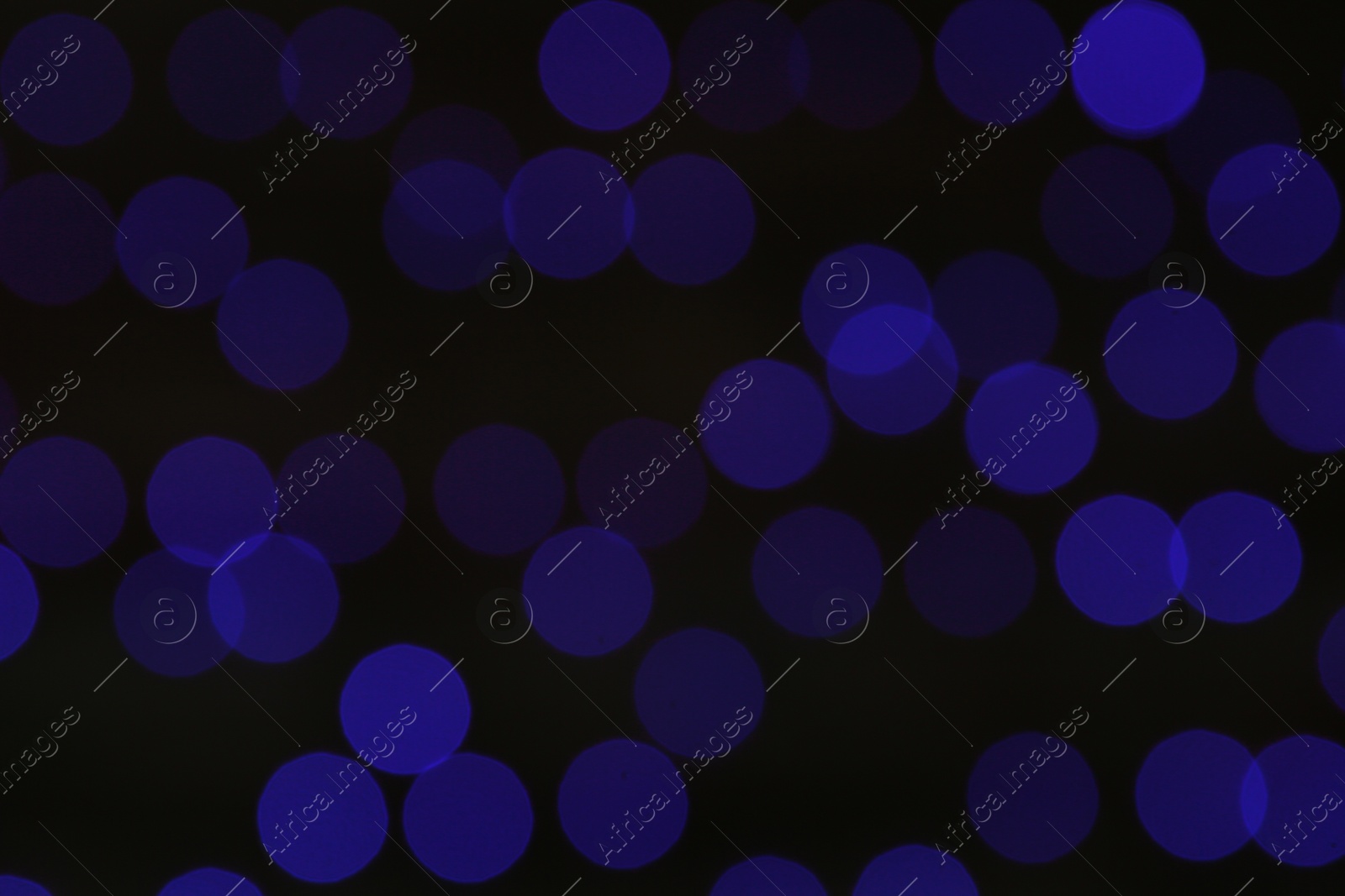 Photo of Blurred view of blue Christmas lights on dark background