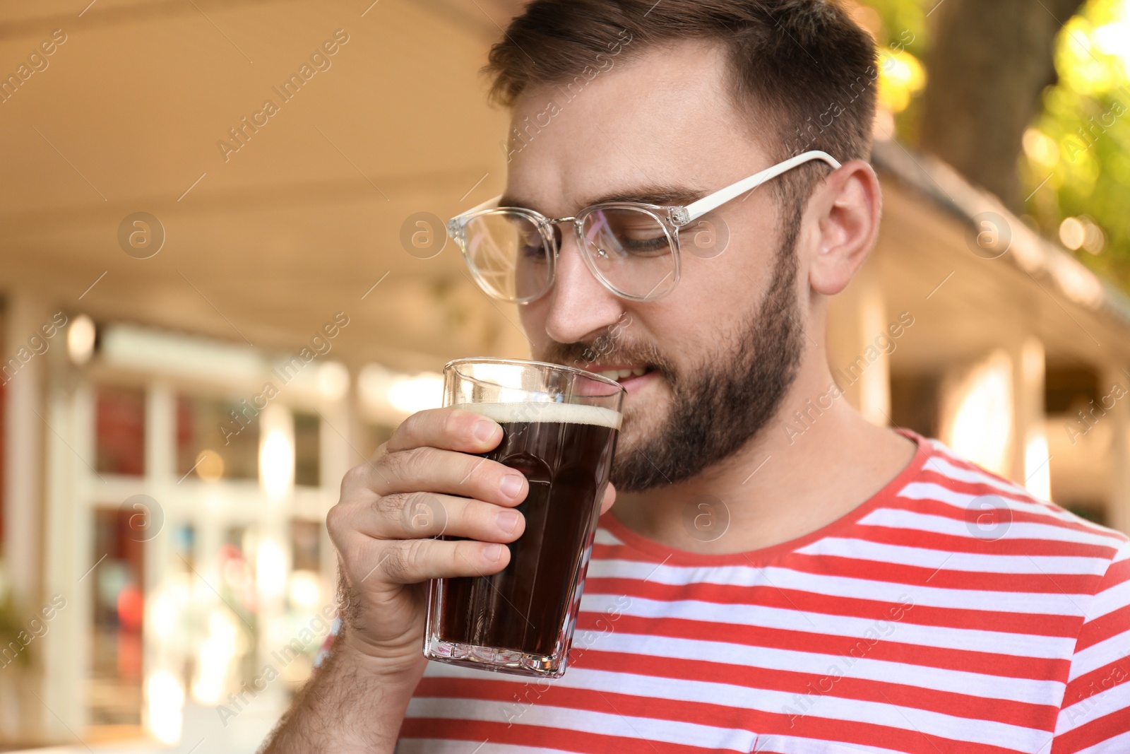 Photo of Handsome man with cold kvass outdoors. Traditional Russian summer drink