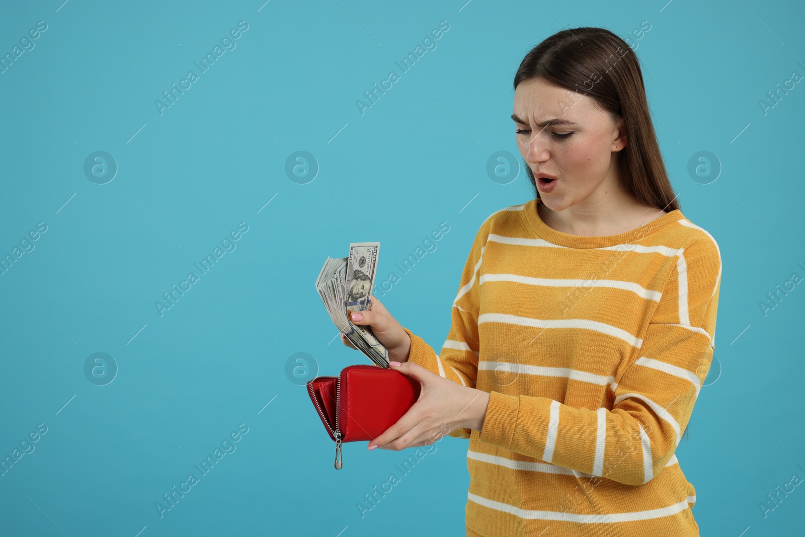 Photo of Woman putting money into wallet on light blue background, space for text