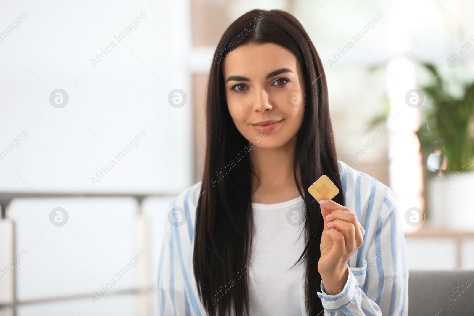 Photo of Happy young woman with nicotine patch at home