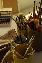 Different brushes and paints on white table indoors. Artist's workplace